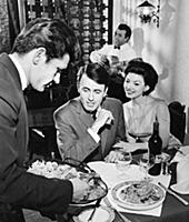 A waiter serves paella to a couple at a Spanish re