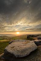 View of gritstone tor overlooking valley at sunset