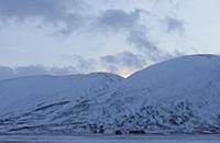View of snow covered valley and mountains at sunse