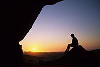 Namibia, Lone figure watching sunset from rock ren