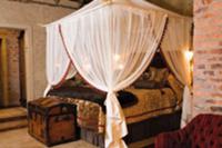 A double bed with a canopy and a trunk at the end 