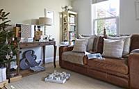Scatter cushions on brown leather sofa below windo