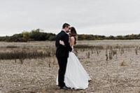 Romantic young bride and groom hugging in field, f