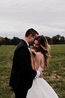 Romantic young bride and groom hugging in field