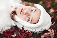 Girl in white hooded top lying on grass amongst au