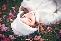 Girl in white hooded top with eyes closed, lying o