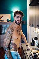 Mid adult man with tattooed chest preparing breakf
