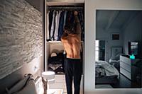 Mid adult man selecting shirt from wardrobe, rear 