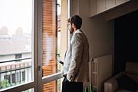 Mid adult man holding smartphone gazing out throug