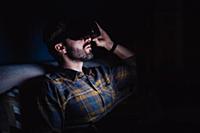 Bearded mid adult man sitting on sofa in darkness 