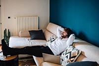 Mid adult man reclining on sofa listening to headp