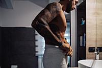Mid adult man with tattoos putting towel around wa