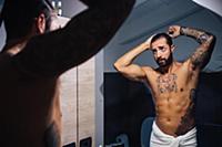 Mid adult man with tattoos combing hair at bathroo