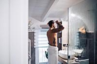 Mid adult man with tattoos combing hair at bathroo