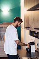 Mid adult man pouring coffee from coffee machine o