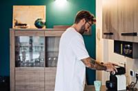 Mid adult man preparing coffee machine on kitchen 