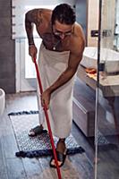 Mid adult man wrapped in towel cleaning bathroom f