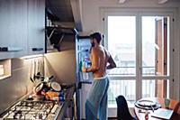 Mid adult man removing bottled water from fridge
