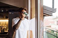 Mid adult man drinking coffee while looking out th