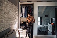 Mid adult man with tattooed chest getting shirt fr