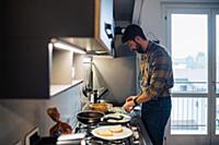 Mid adult man preparing food at kitchen hob