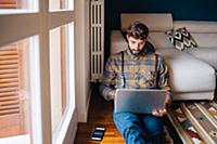 Mid adult man sitting on living room floor looking