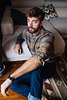 Mid adult man sitting on living room floor gazing