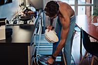 Mid adult man preparing meal removing colander fro
