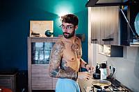 Mid adult man with tattooed chest preparing breakf