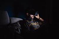Bearded mid adult man sitting on sofa in darkness 