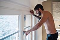 Mid adult man looking down through apartment windo