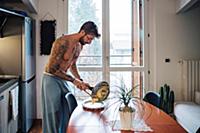 Mid adult man with tattoos serving omelette from f