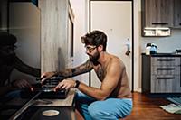 Mid adult man with tattoos playing vinyl on turnta