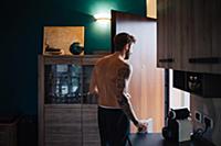 Mid adult man with tattooed arm leaving kitchen, r
