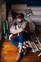 Mid adult man sitting on living room floor looking