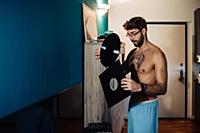 Mid adult man with tattooed chest removing vinyl r