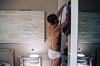 Mid adult man with tattoos selecting shirt from wa