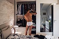 Mid adult man with tattoos selecting clothes from 