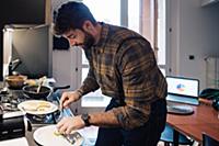 Mid adult man plating food at kitchen counter