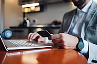 Mid adult man sitting at kitchen table with laptop