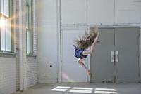 Teenage girl with long brown hair leaping mid air 