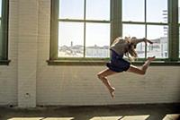 Teenage girl with long brown hair leaping mid air 