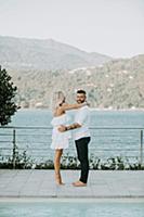 Romantic mid adult couple barefoot on poolside, po