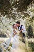 Romantic groom kissing bride on cheek in woodland