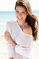 A young woman in a summer jumper on a beach