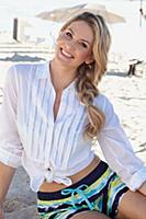 A young blonde woman sitting on a beach wearing a 