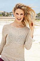 A young blonde woman on the beach wearing a beige 