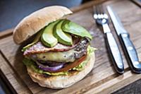Burger with avocado slices, cheese, bacon, onions,