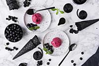 Liquorice ice cream with blackcurrants on white de