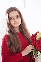 Девочка позирует в студии с букетом цветов